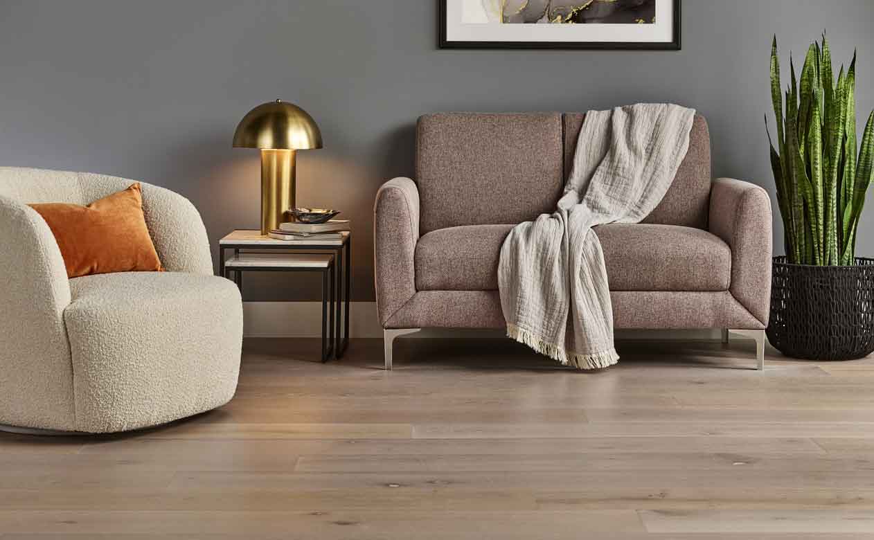 hardwood flooring in a living room with a neutral love seat and accent chair